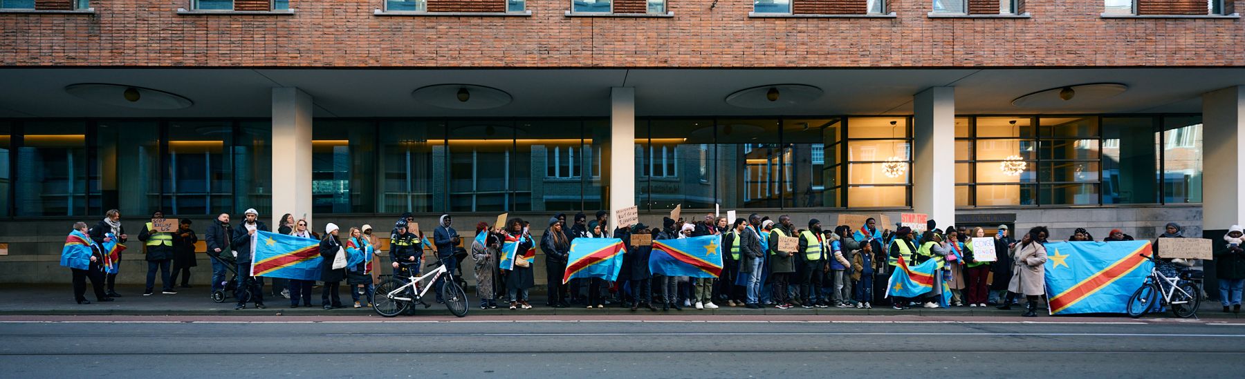 Demonstranten met Congolese vlaggen voor een gebouw
